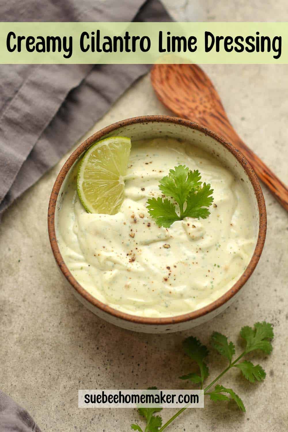 A bowl of creamy cilantro lime dressing with a wedge of lime.