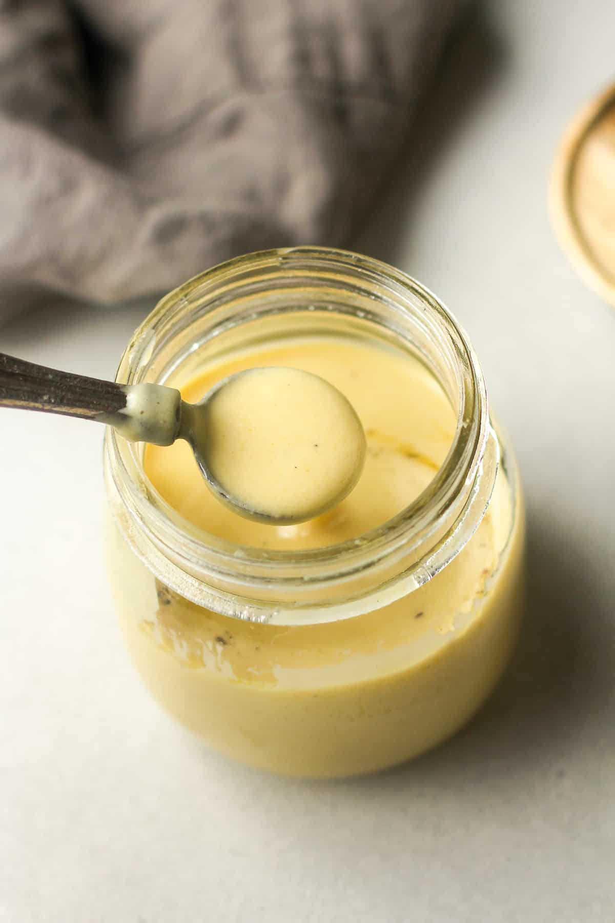 A teaspoon lifting out some dressing from a jar.