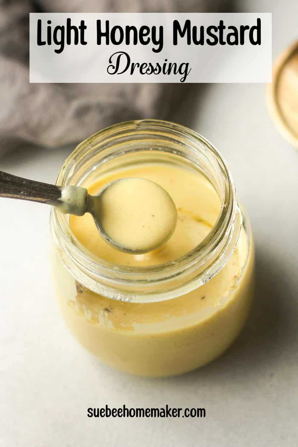 A spoonful of honey mustard dressing over a mason jar.