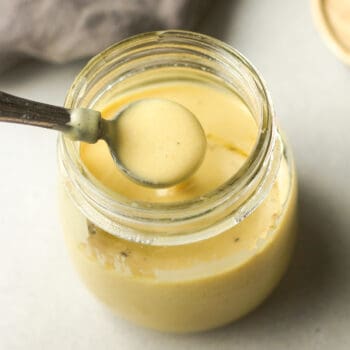 A spoonful of light honey mustard dressing over a jar.