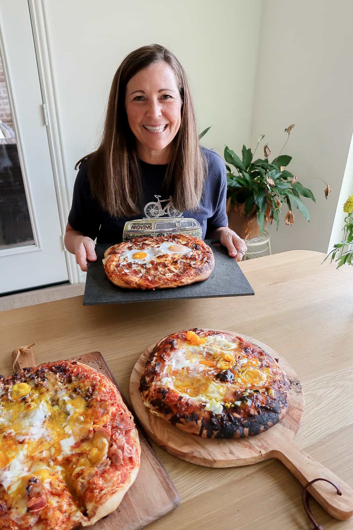 SueBee Homemaker holding a board with a breakfast pizza.