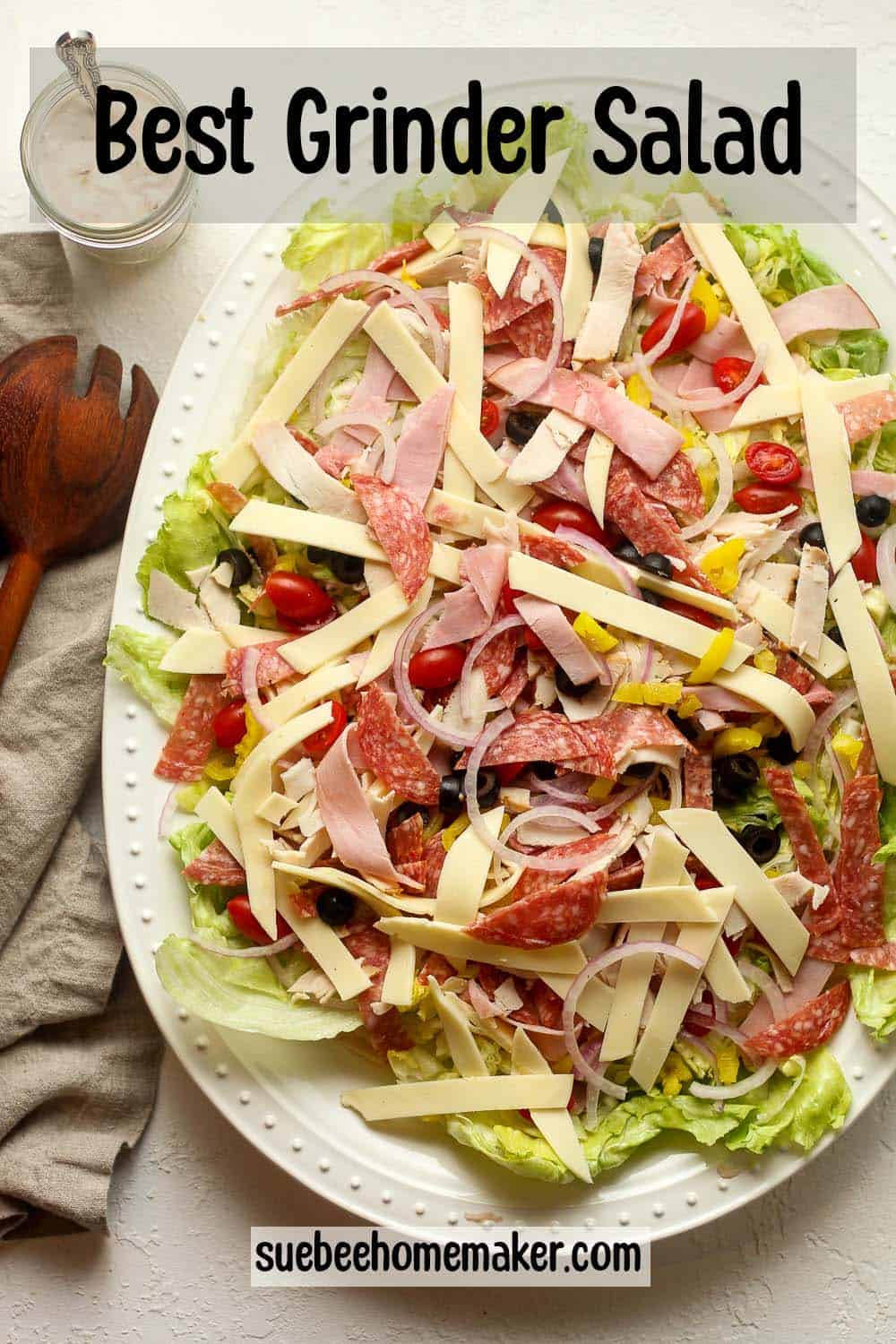 A large platter of the best grinder salad with a jar of dressing on top.