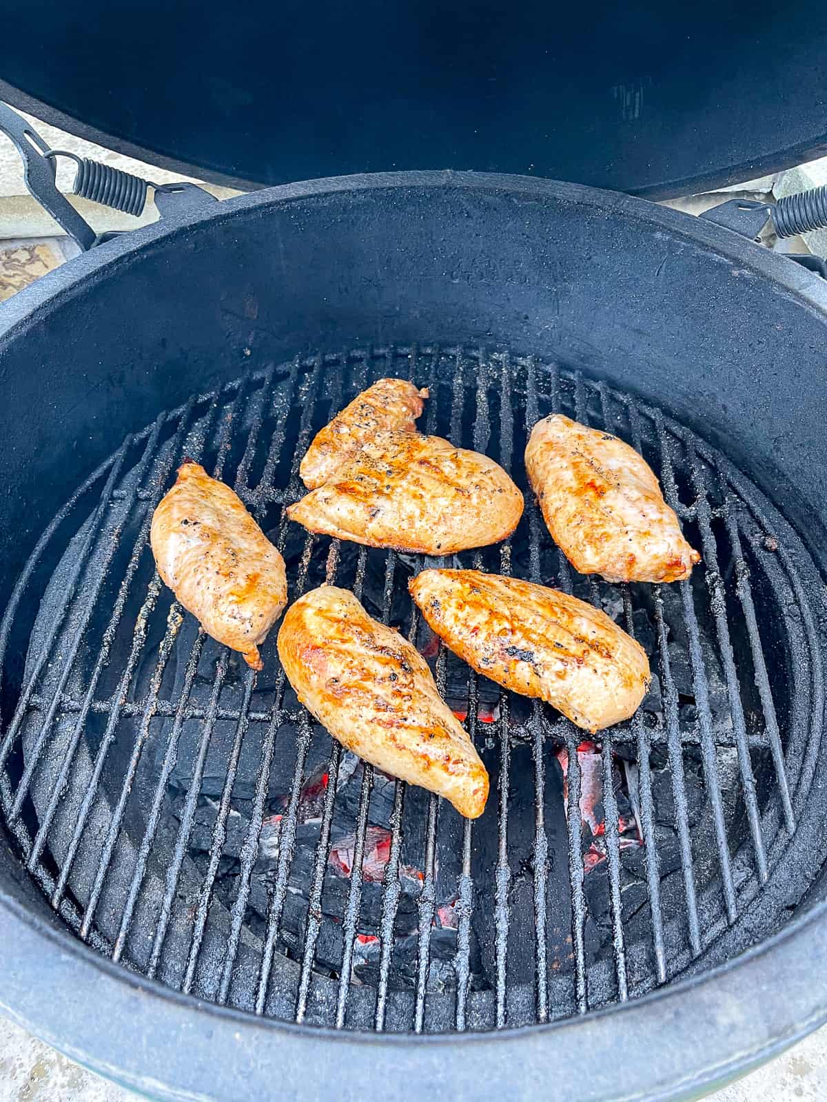 A charcoal grill with chicken on top.