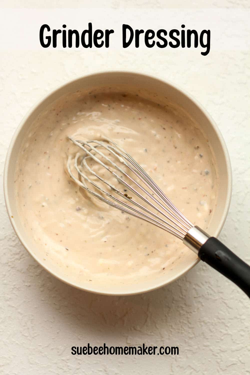 A bowl of the dressing with a whisk inside.