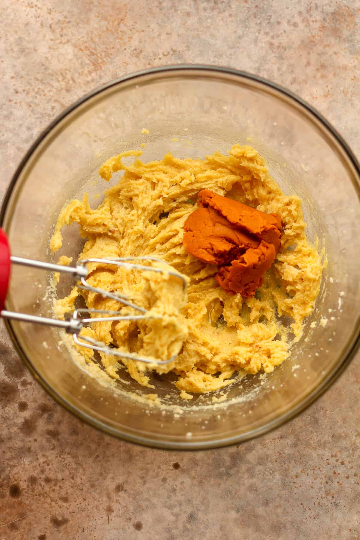 A bowl of the wet ingredients with some dry pumpkin mix.