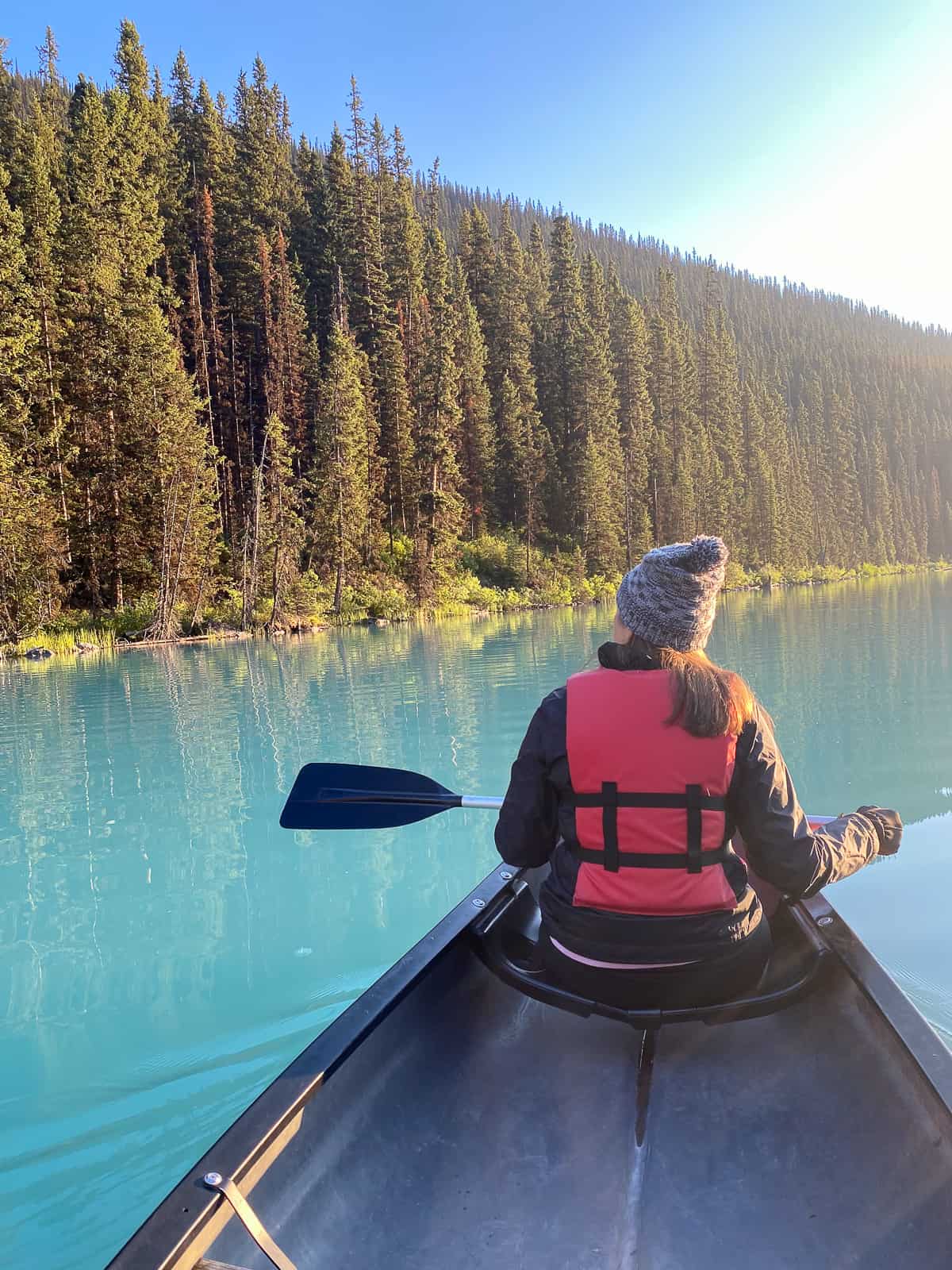 Sue on a canoe beside some trees.
