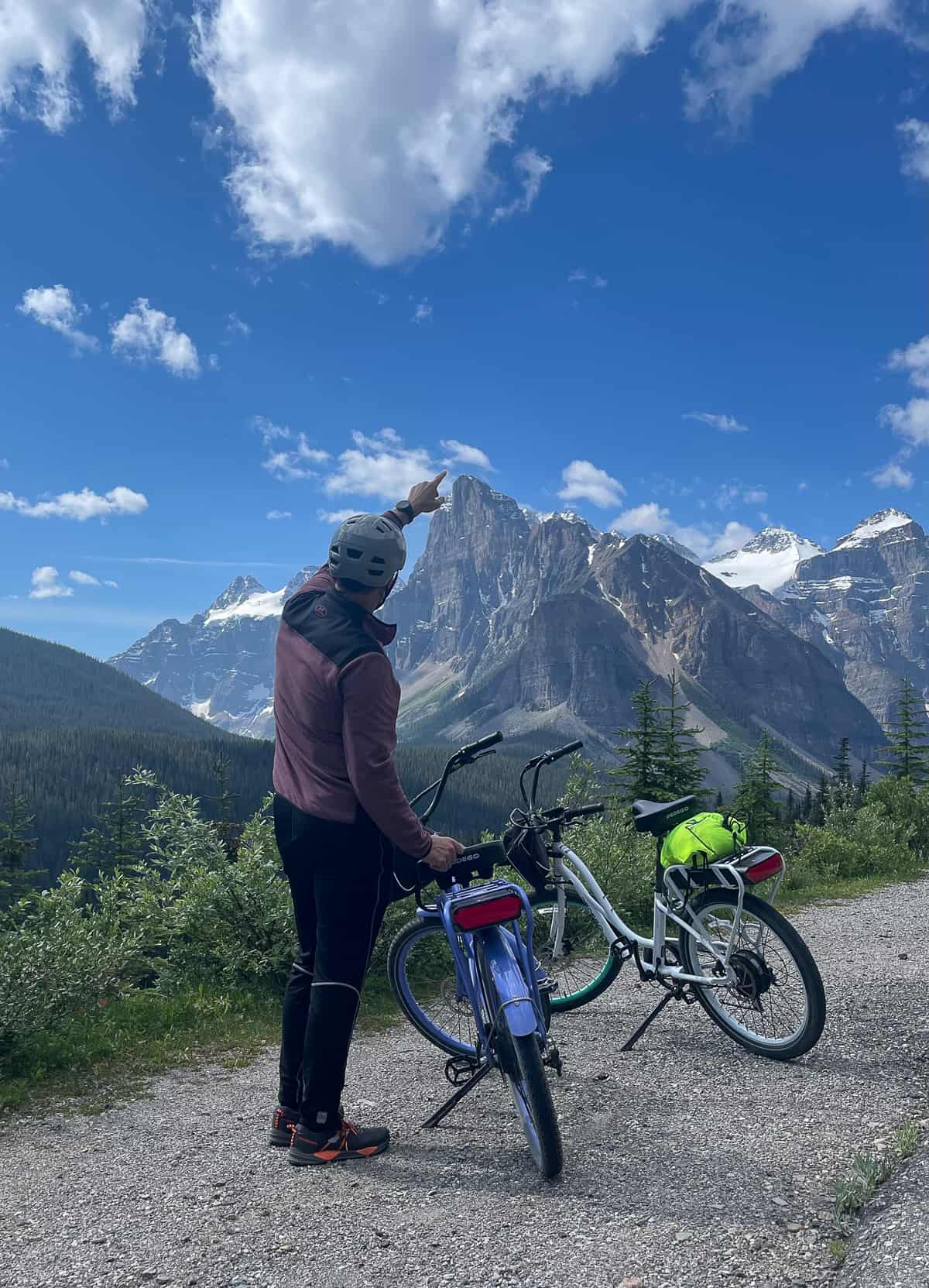 Mike pointing his finger to the top of a mountain beside our e-bikes.