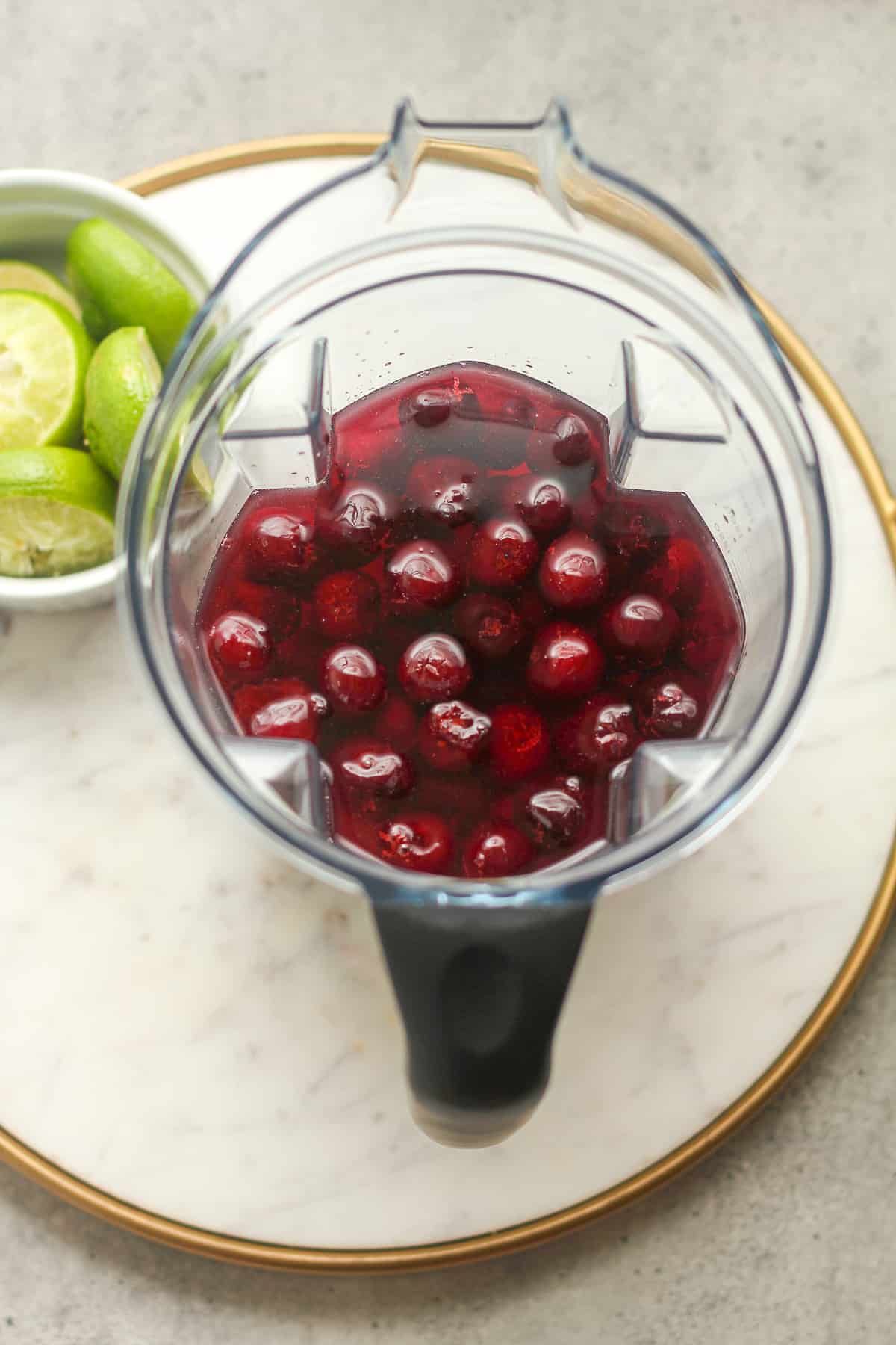 The blender with cherries and liquid.