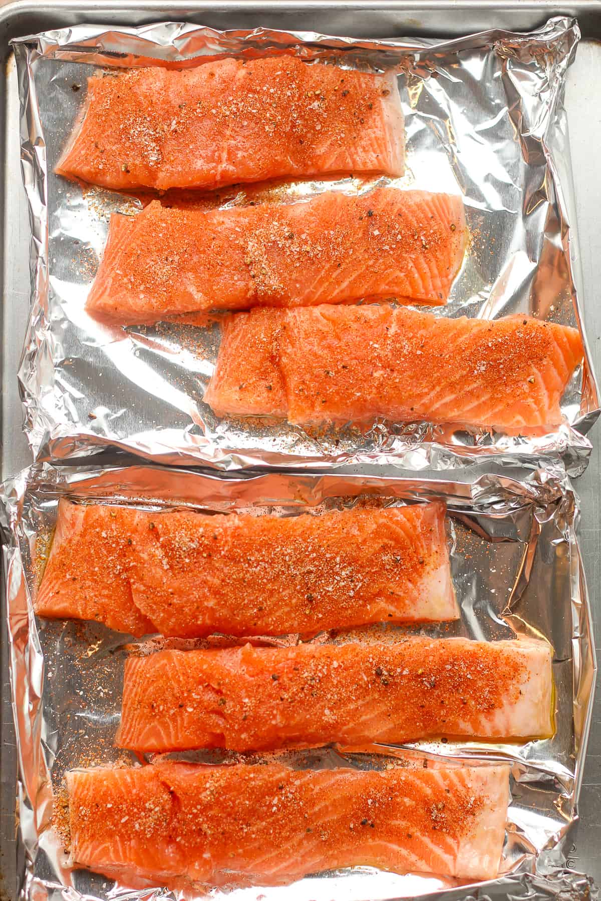 Six pieces of salmon with seasonings on top.