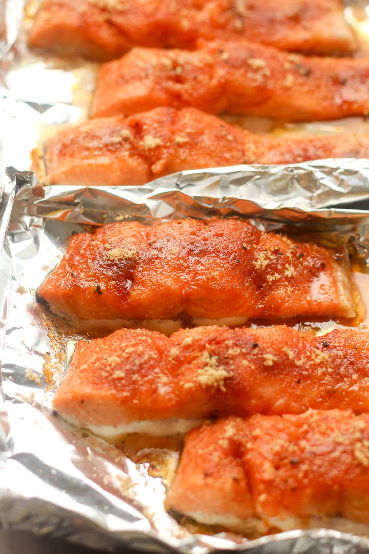 Side view of six pieces of brown sugar smoked salmon on aluminum foil.