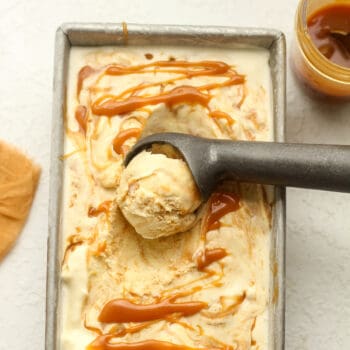 A pan of caramel swirl ice cream with an ice cream scoop.