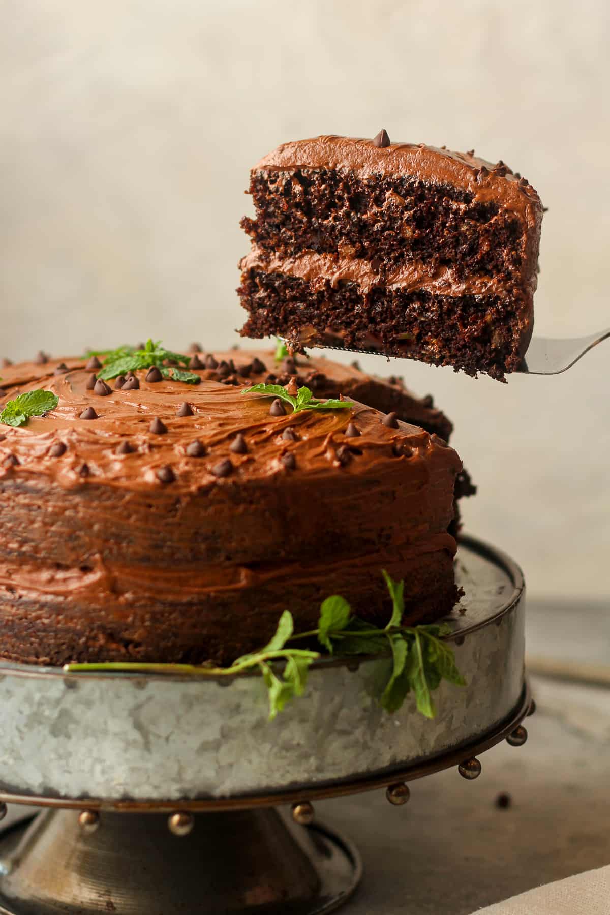 Side view of a chocolate buttermilk cake with a slice being lifted out.