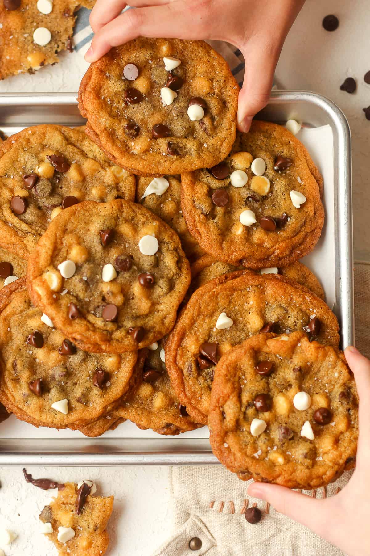 A tray of cookies with hands grabbing cookies.