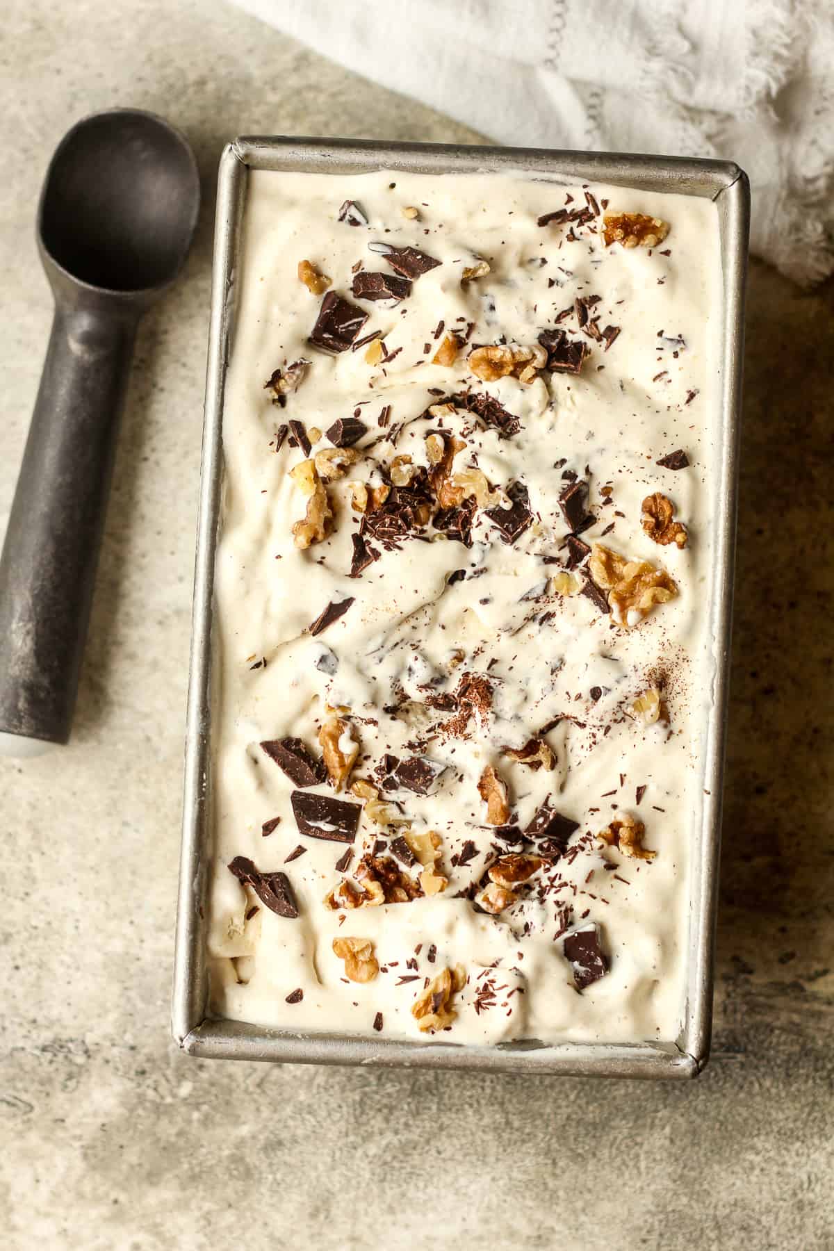 A rectangular pan with chunky monkey ice cream and an ice cream scoop.