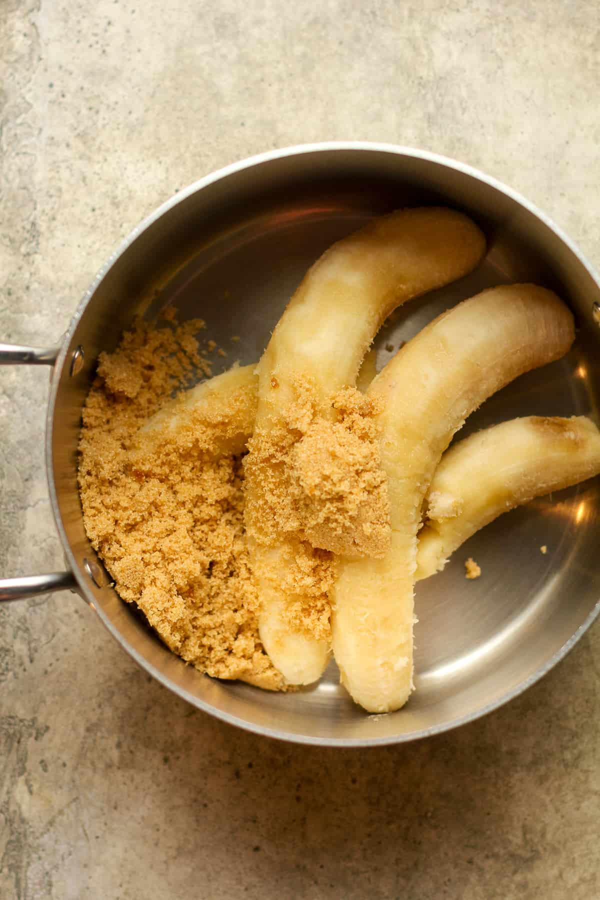 The ripe bananas plus brown sugar in a pan.