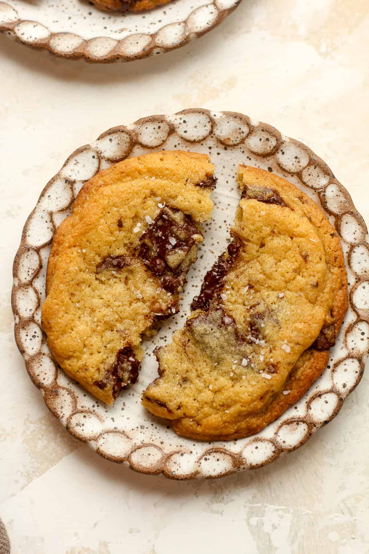 A small plate of a halved dark chocolate chunk cookie.