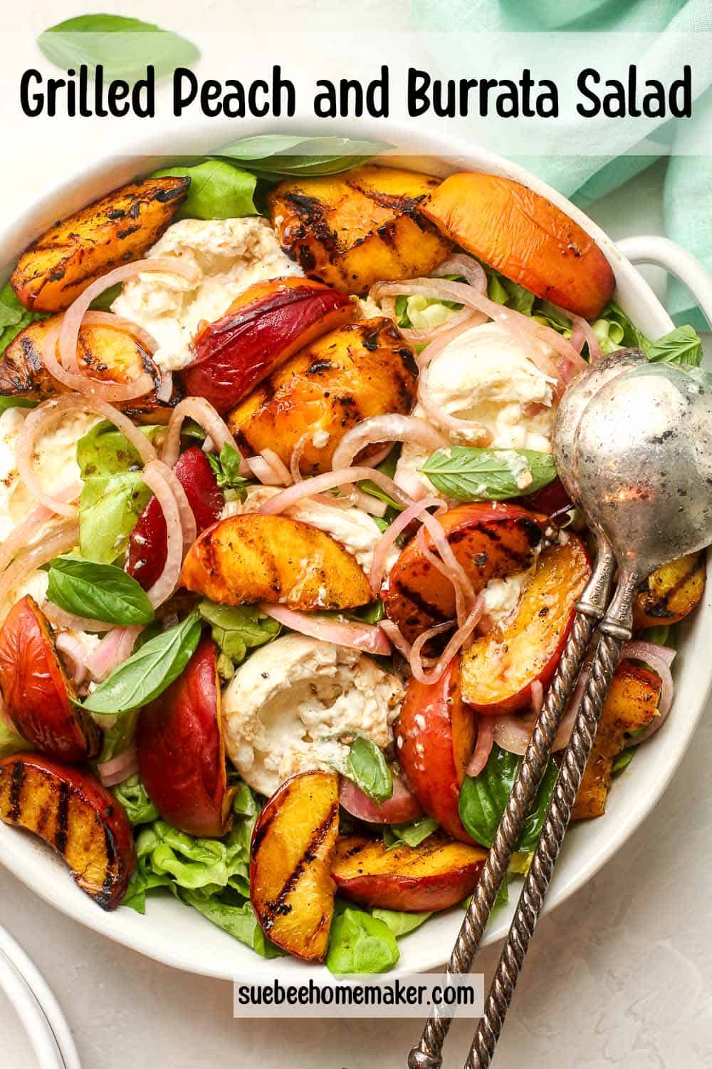 A serving bowl filled with grilled peach and burrata salad with salad tongs.