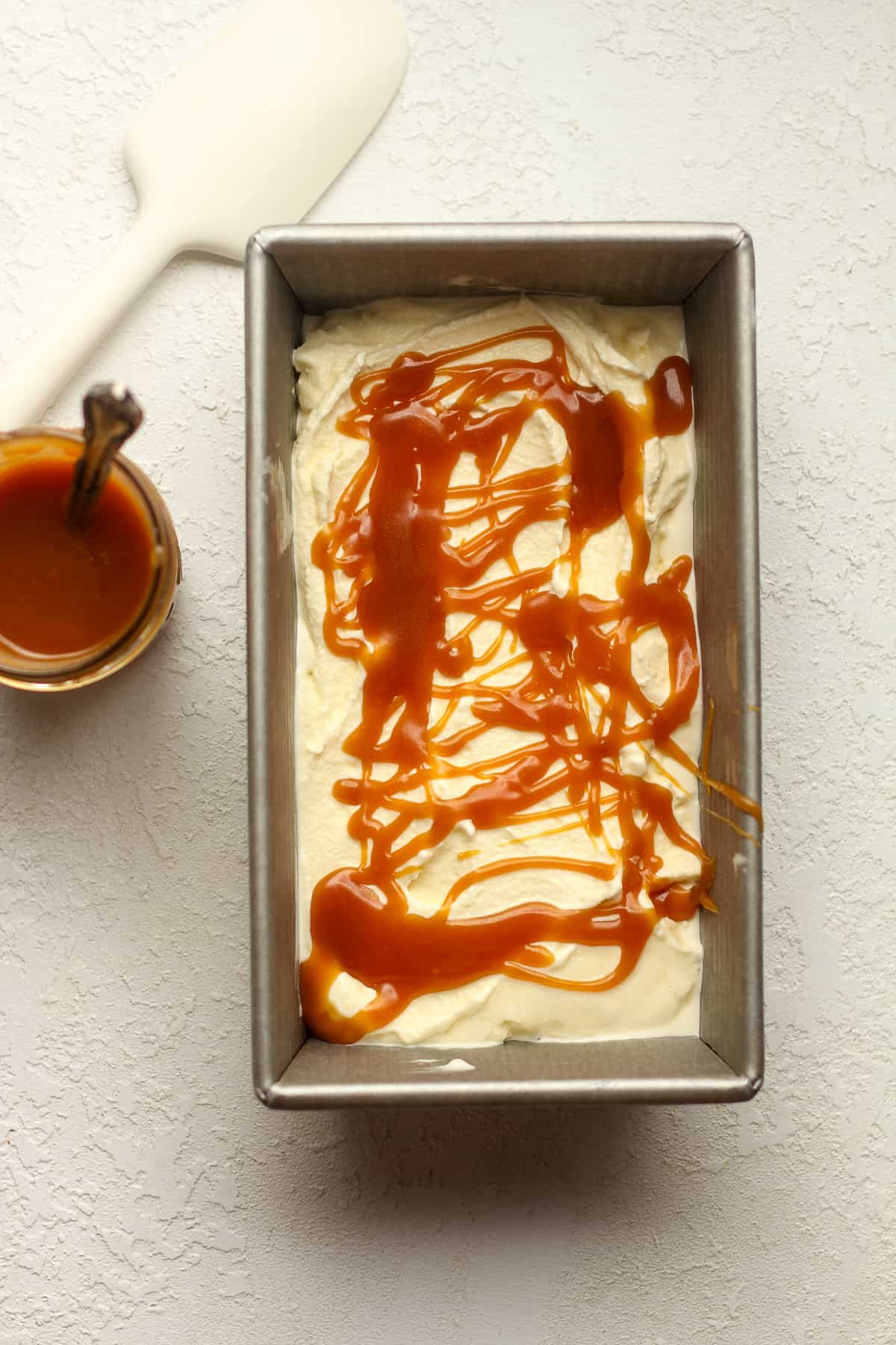 A pan of ice cream with a layer of caramel drizzle.