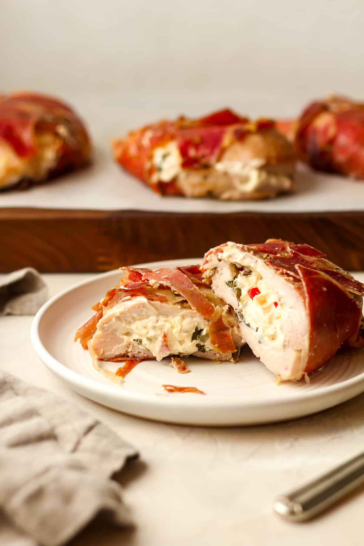 Side view of a plate of a halved parma wrapped chicken breast stuffed with goat cheese.