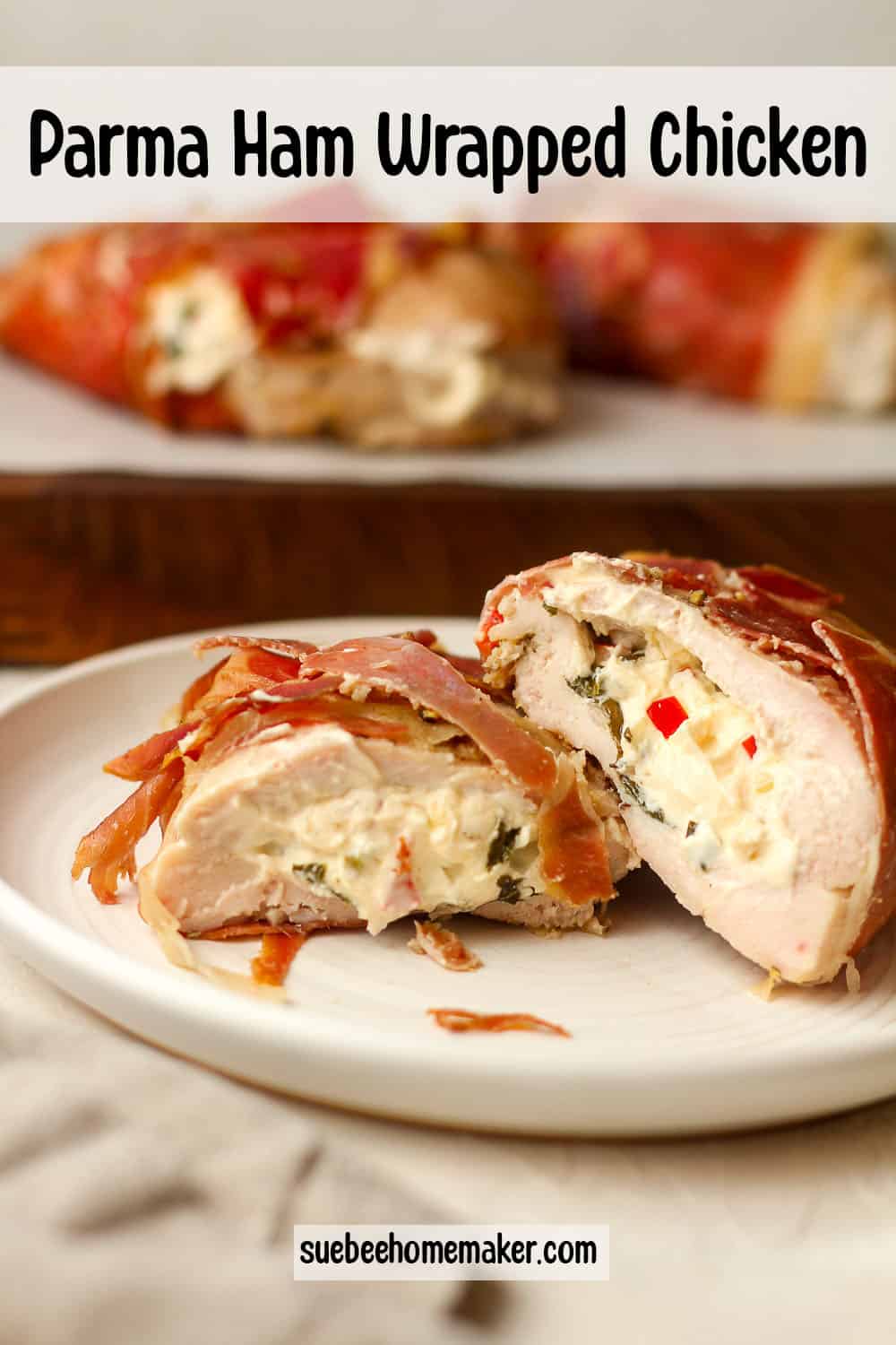 Side view of a plate of a halved goat cheese stuffed chicken breast wrapped in parma ham.