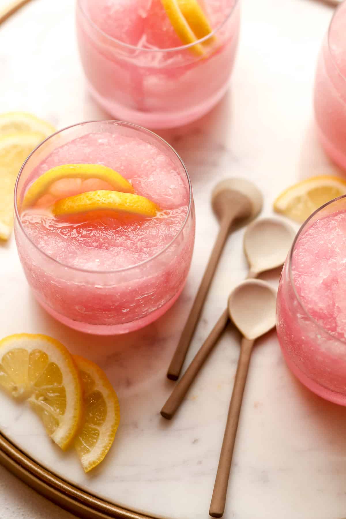 Overhead view of four glasses of pink lemonade slushies.