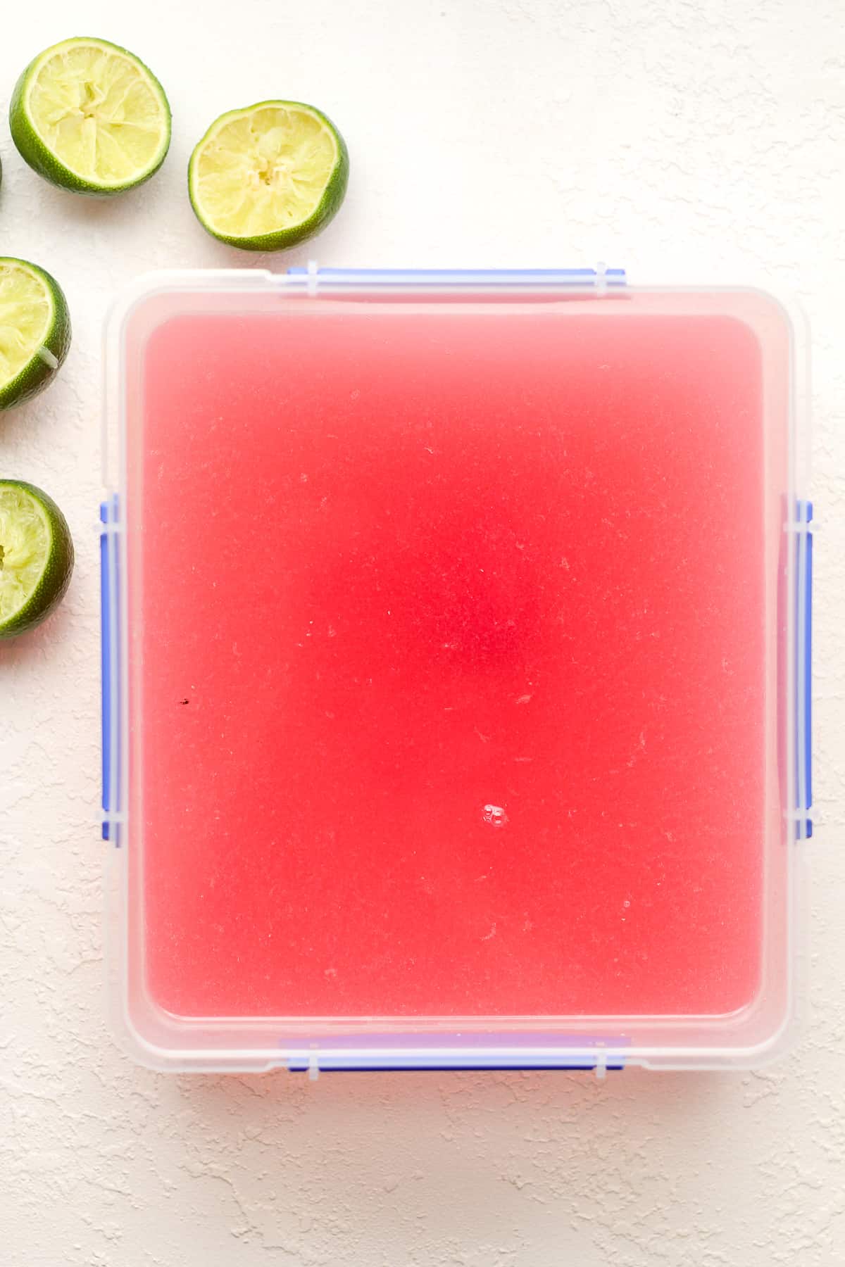 The liquid slush mixture in a rectangular container with limes next to it.