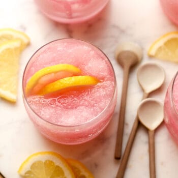 Overhead view of a pink lemonade vodka slush with lemon slices.