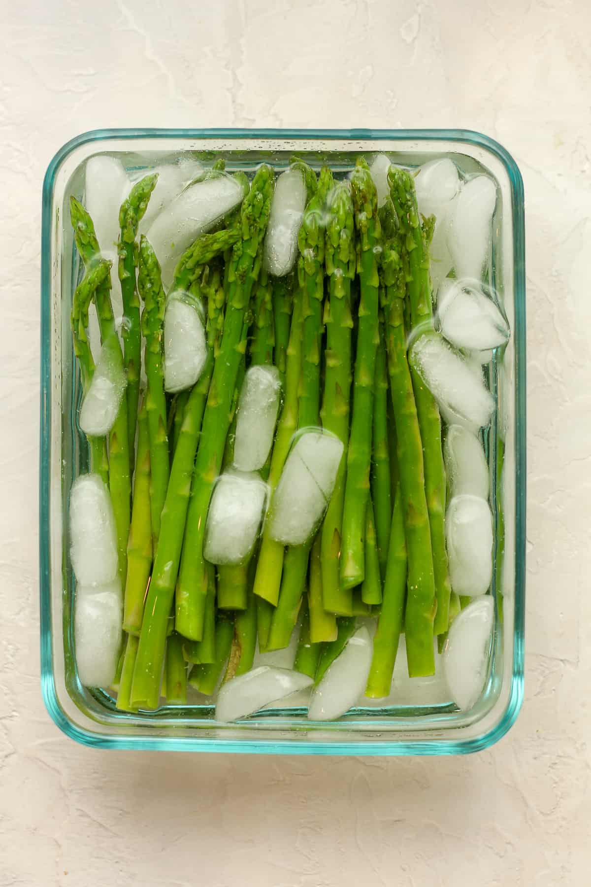 A dish of asparagus with ice water.
