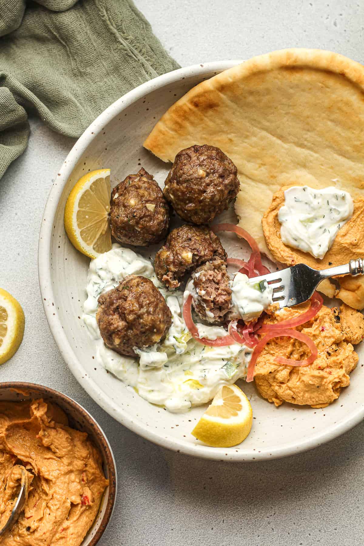 Overhead view of a bowl of Greek meatballs, naan, and sauce.