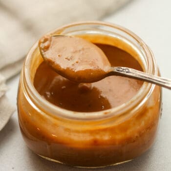 A jar of Thai peanut sauce with a spoonful on top.