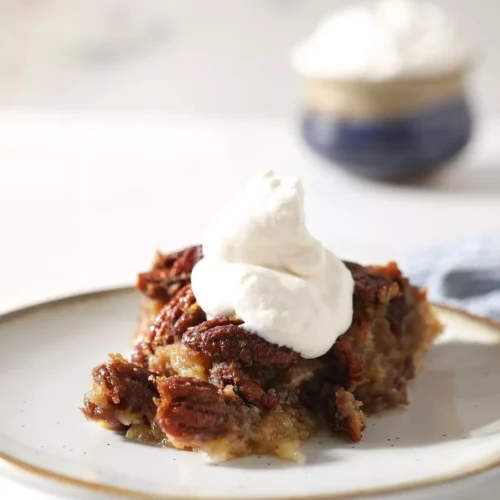 A serving of Bourbon Pecan Pie with cool whip on top.