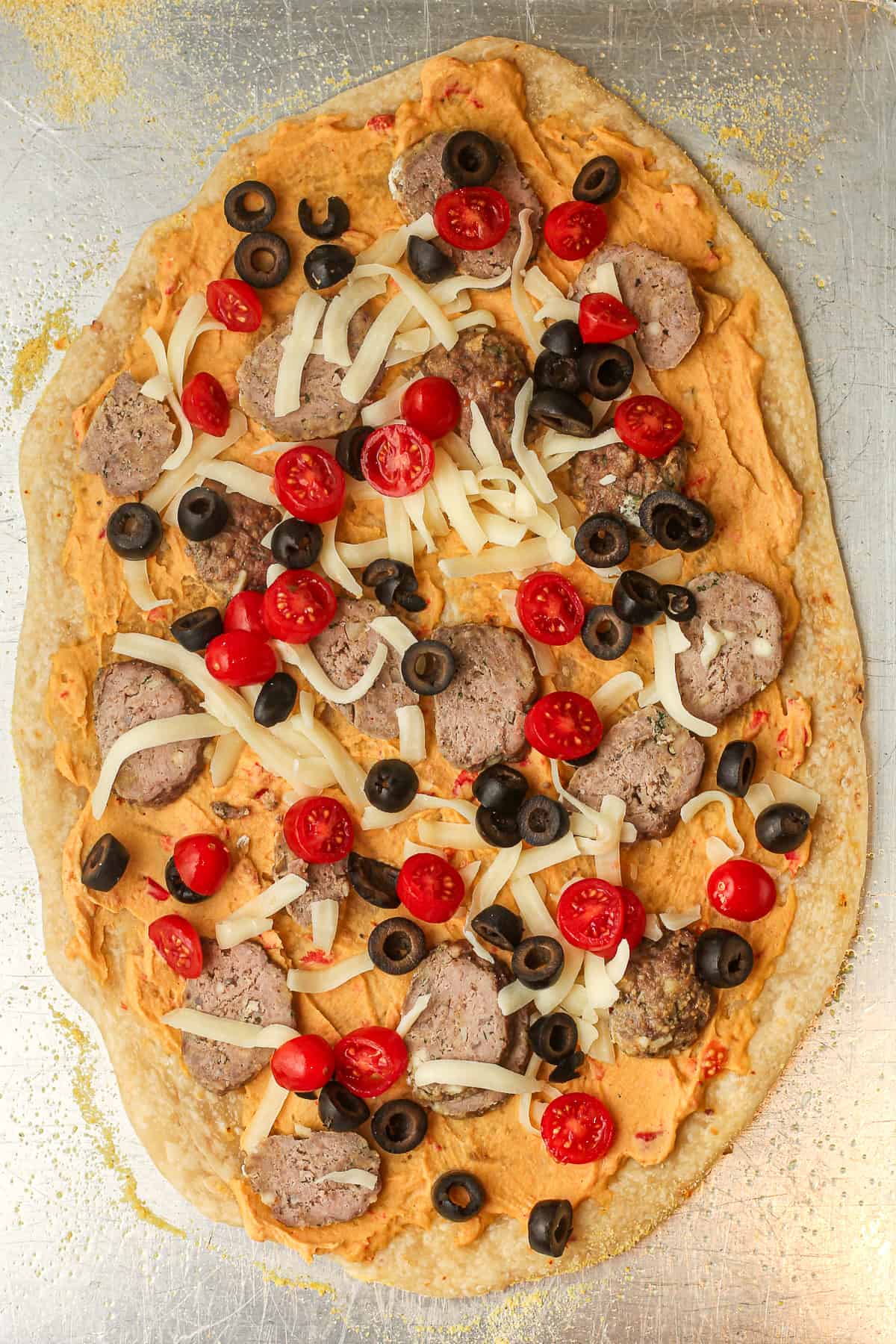 A pan of the flatbread pizza with hummus, lamb, olives, and tomatoes.