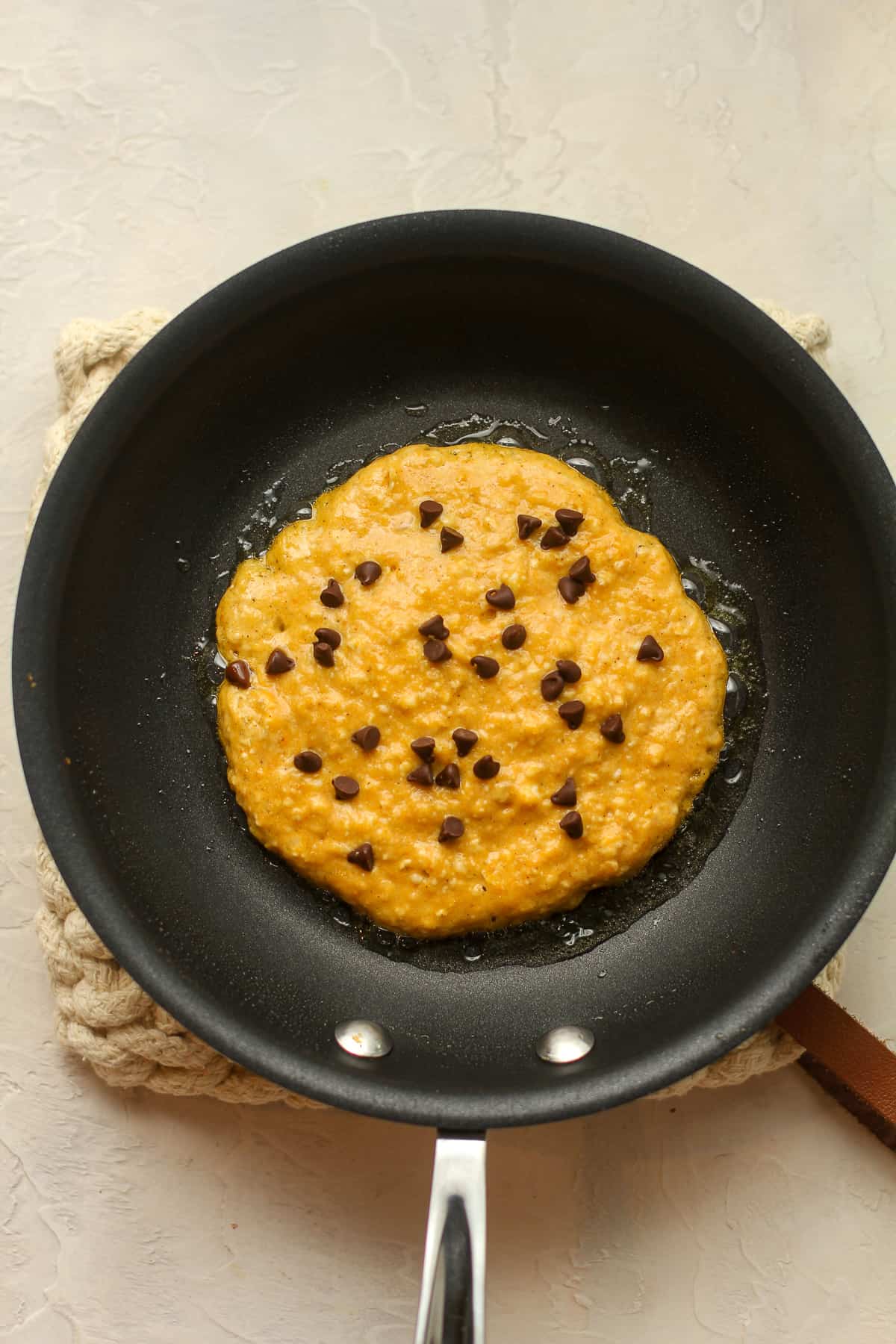 A pan with pumpkin pancake batter and mini chocolate chips on top.