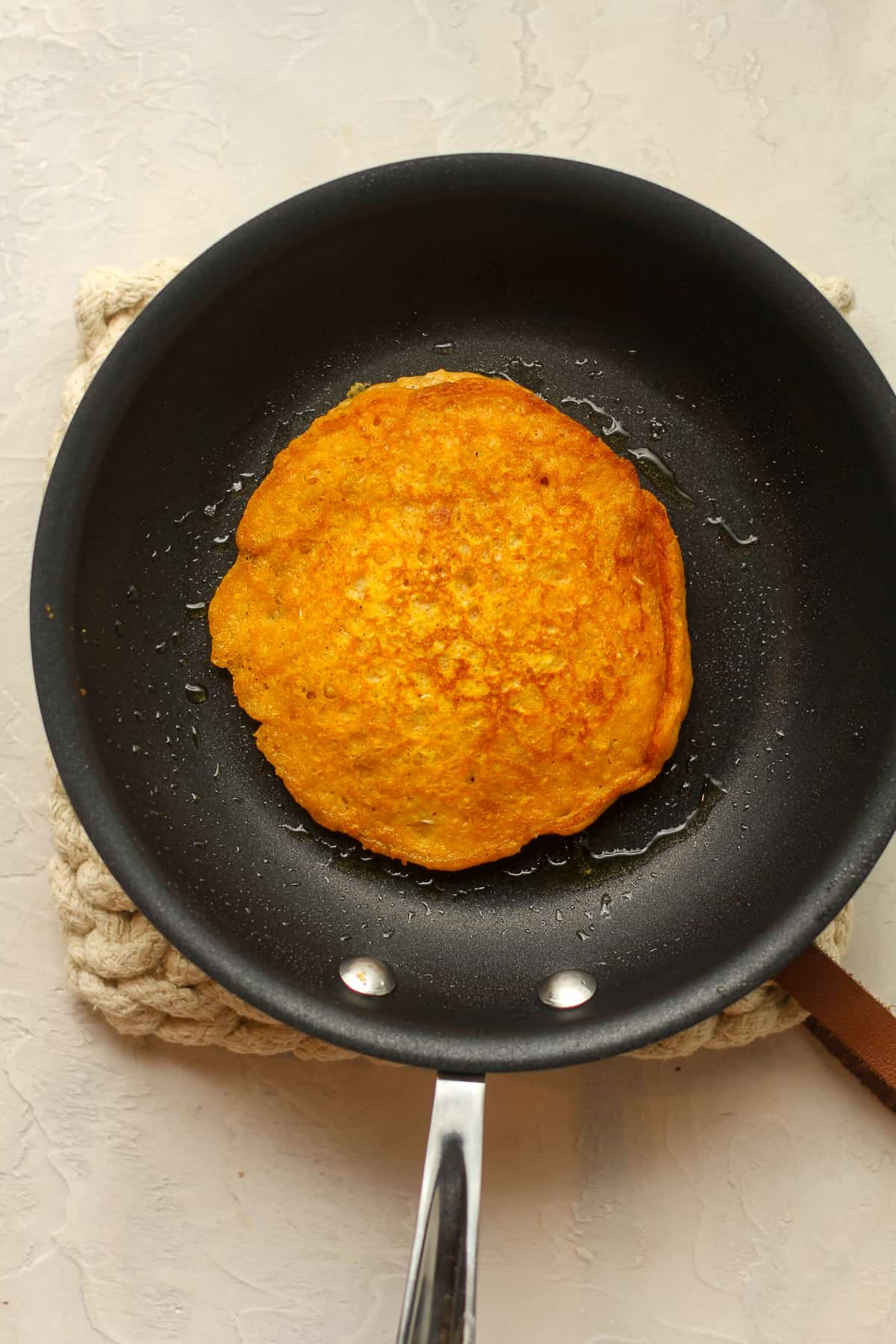 A nonstick pan with a cooked pumpkin pancake.
