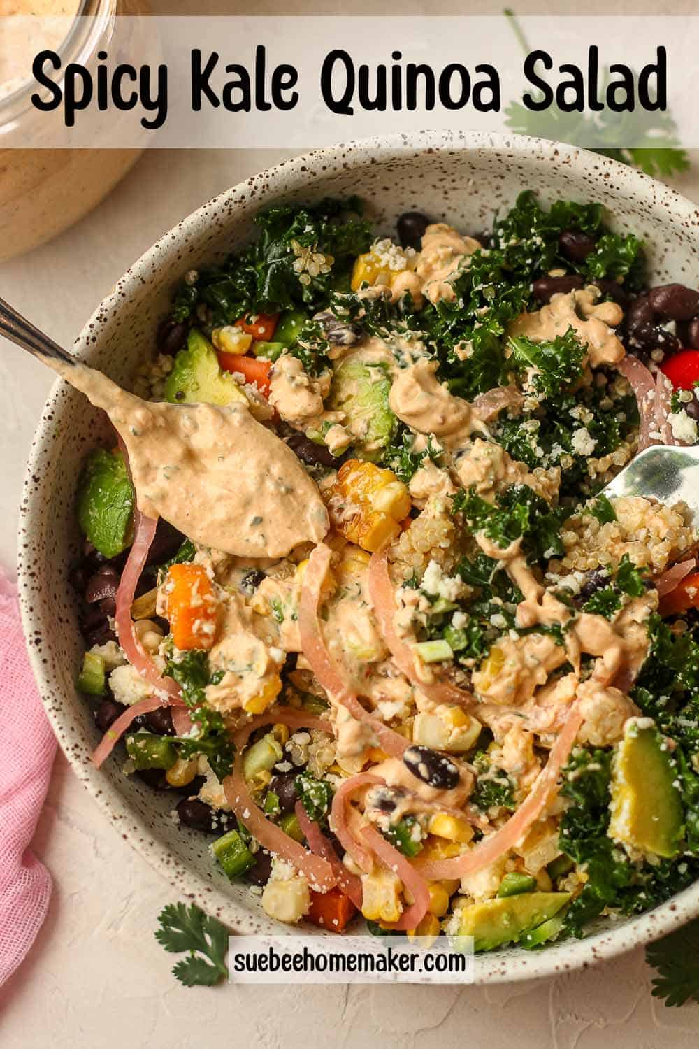 A bowl of spicy kale quinoa salad with a spoonful of dressing.