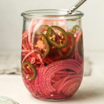 Side view of a jar of spicy pickled onions.