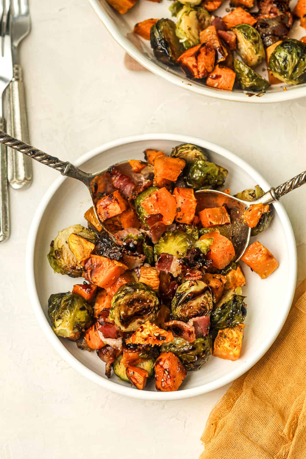 A serving of roasted brussels sprouts and sweet potatoes with bacon and balsamic glaze.