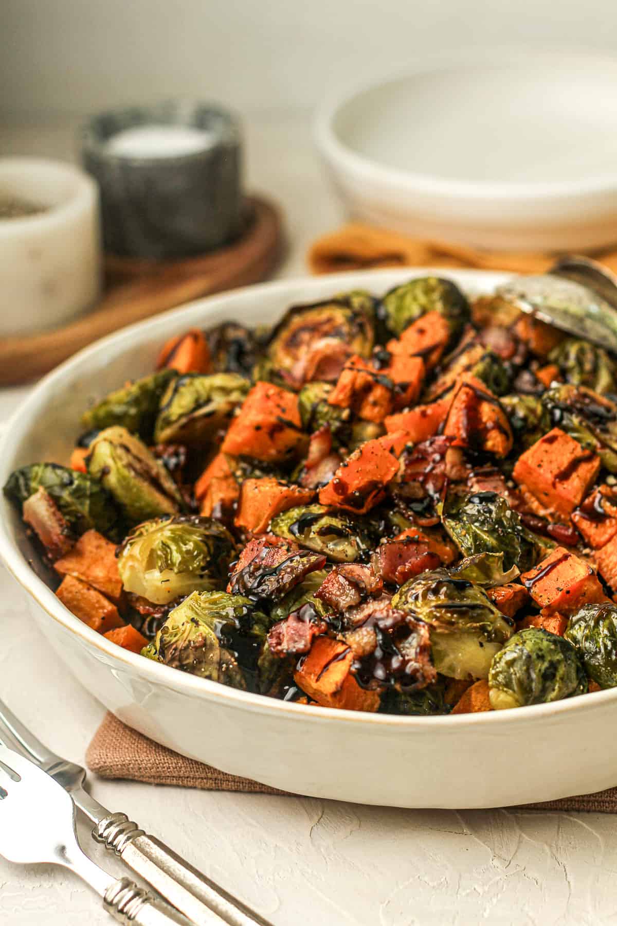 Side view of a serving bowl of roasted veggies with balsamic glaze.