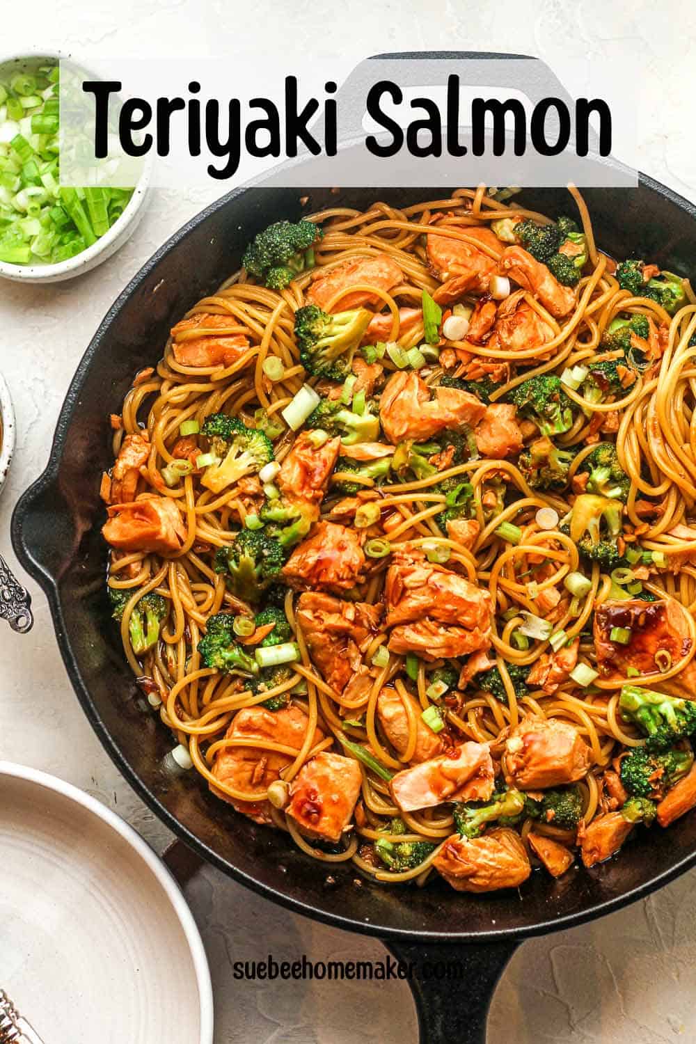 A large skillet of teriyaki salmon with noodles and broccoli florets.