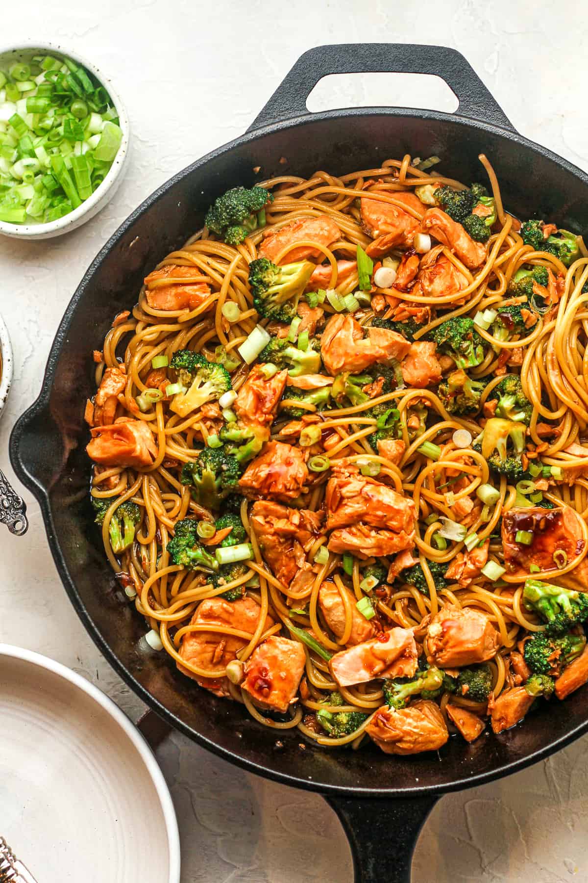 A skillet of the teriyaki salmon with noodles and broccoli.
