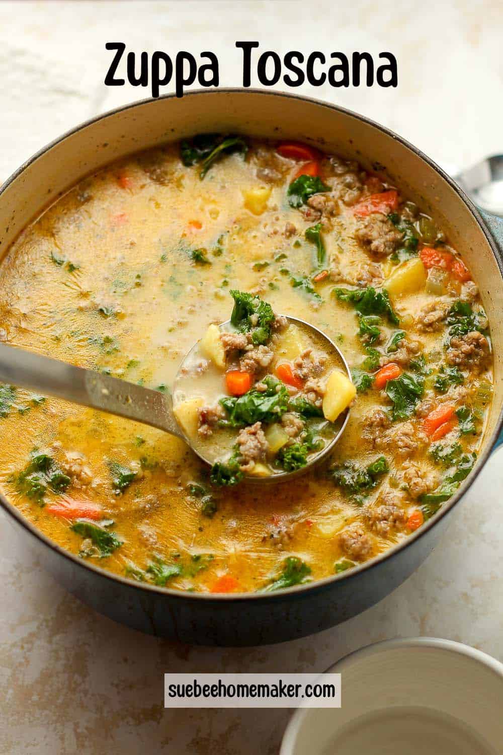 A pot of Zuppa Toscana soup with a soup ladle lifting some out.