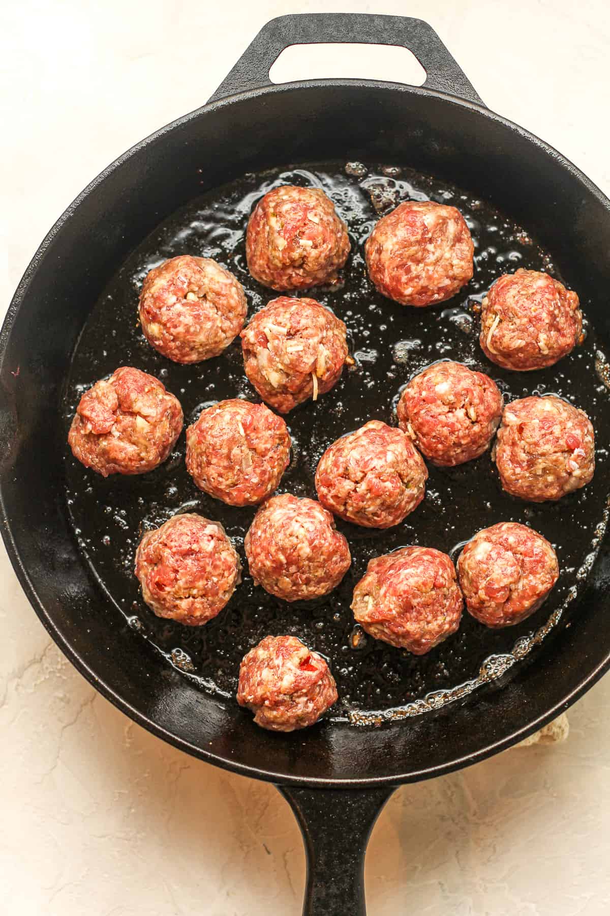 A large skillet of the raw meatballs.