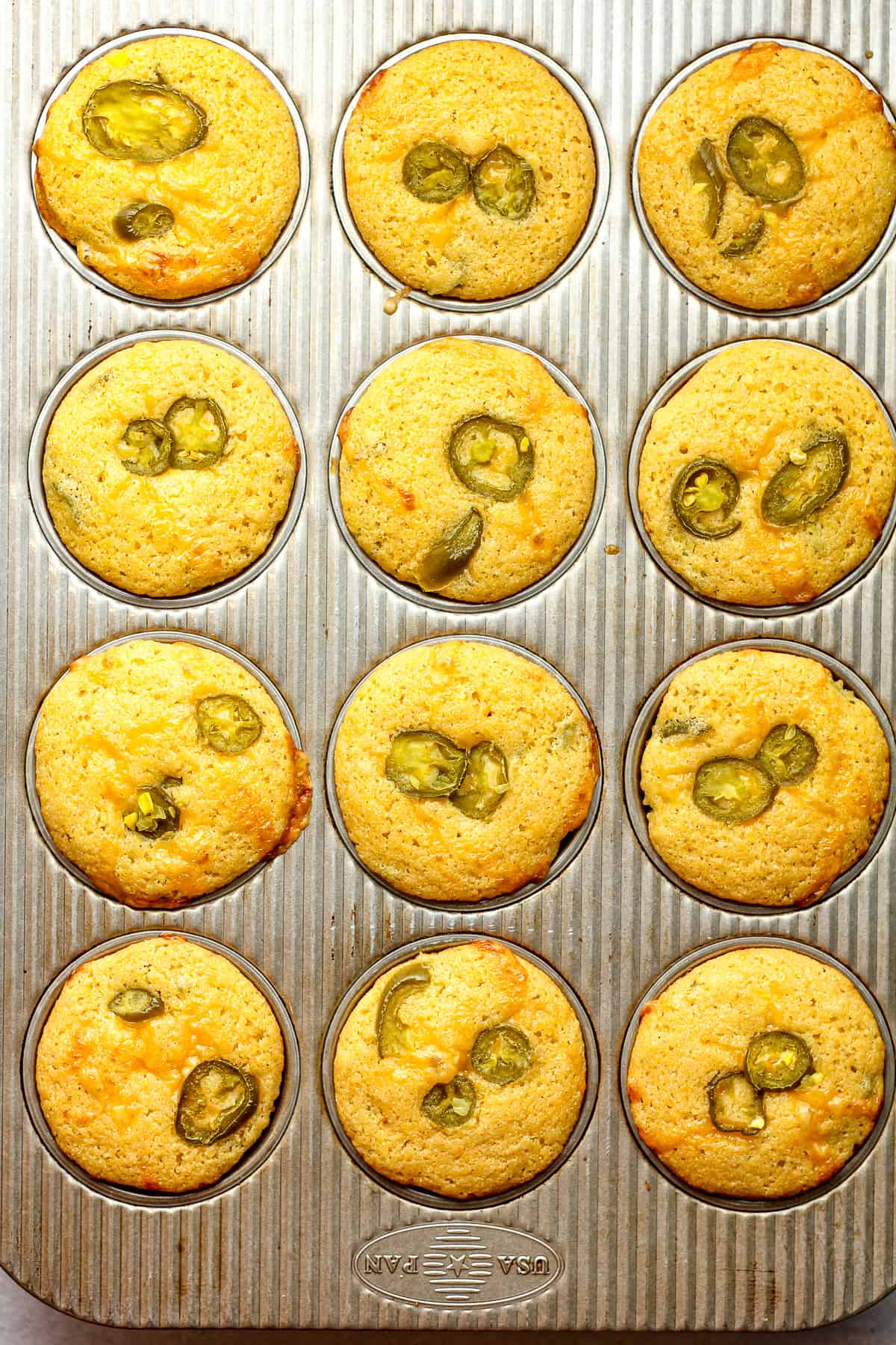 A muffin pan with 12 cornbread muffins.
