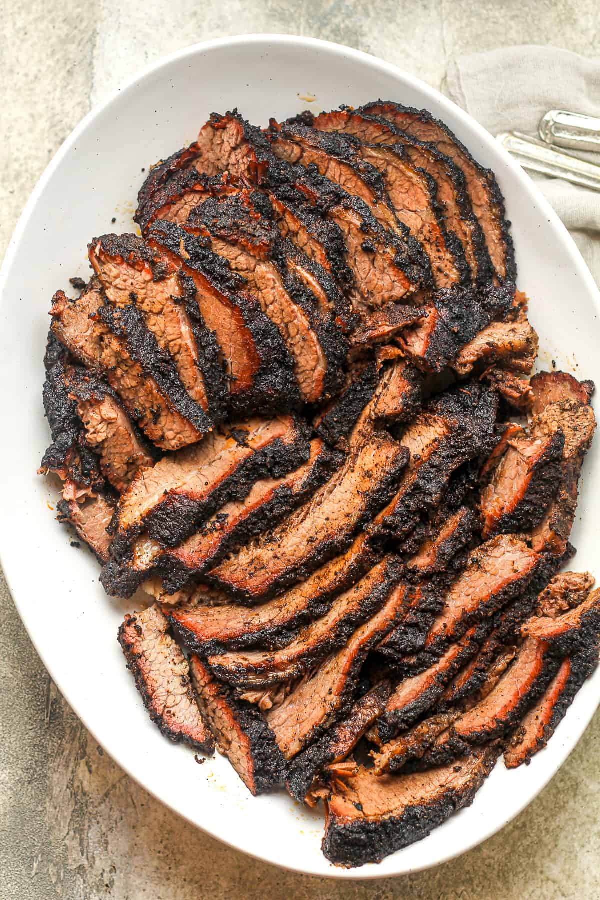 An oblong dish of sliced, smoked brisket.