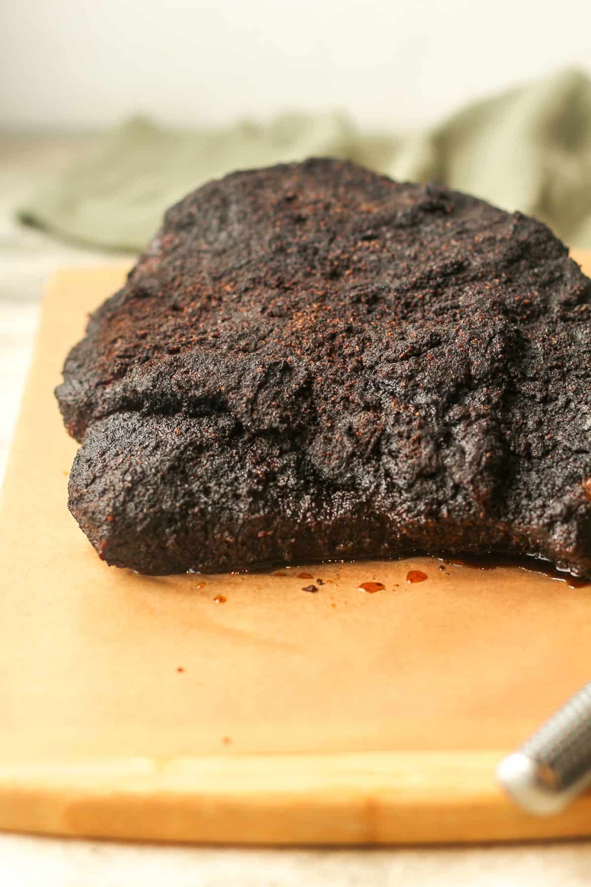 Side view of a cooked brisket on a board.