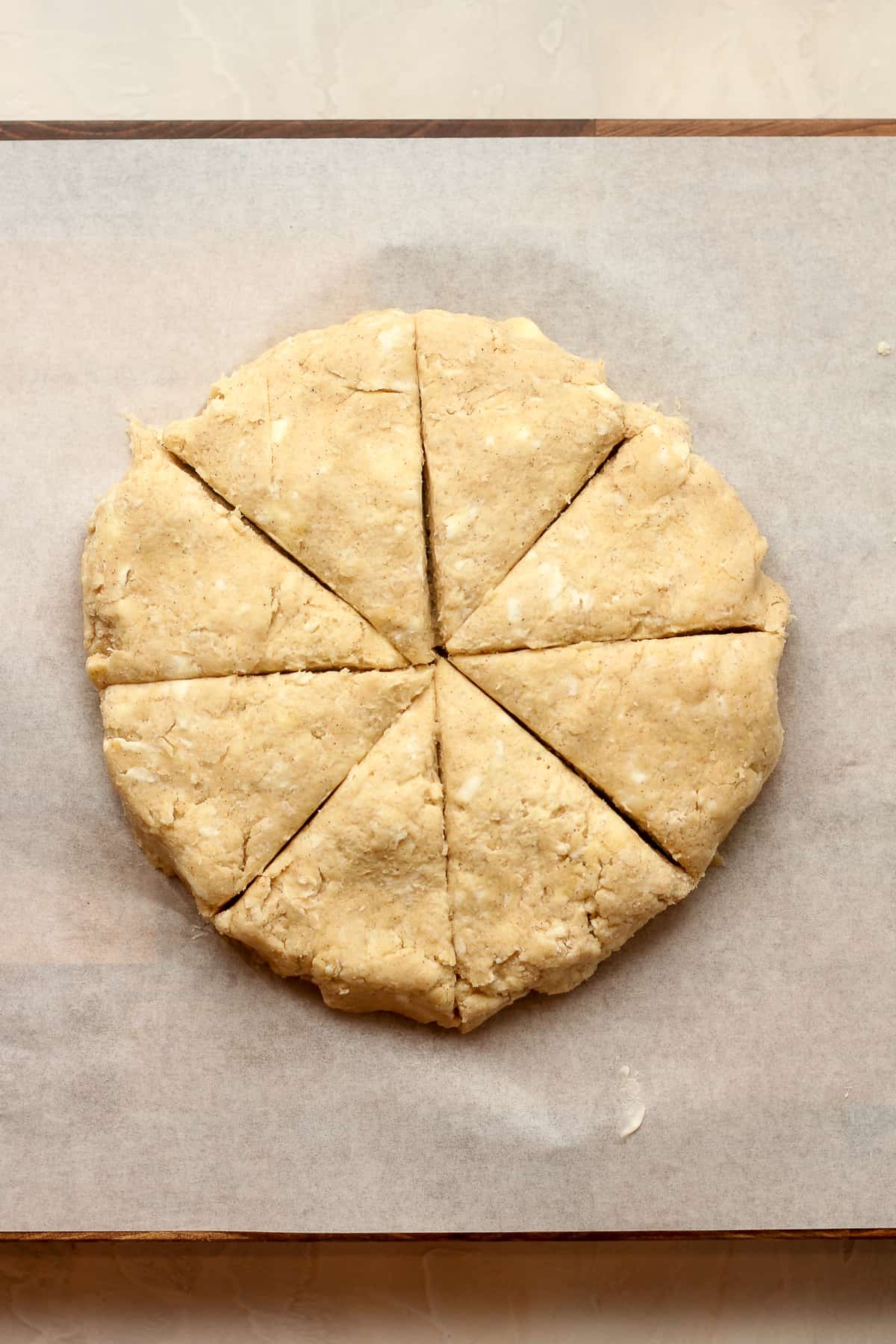 Overhead view of a round of scone dough, cut into 8 equal triangles.