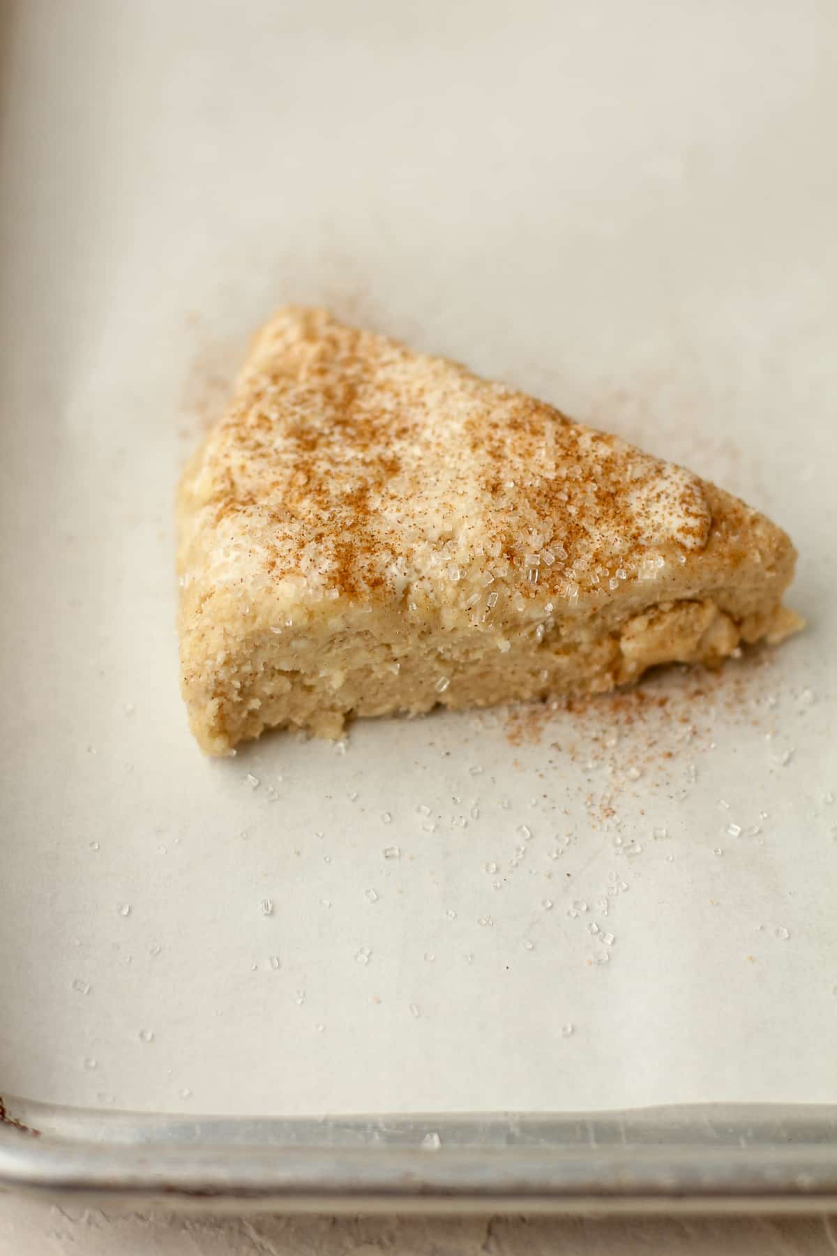 Side view of a scone triangle with sparkling sugar and cinnamon.