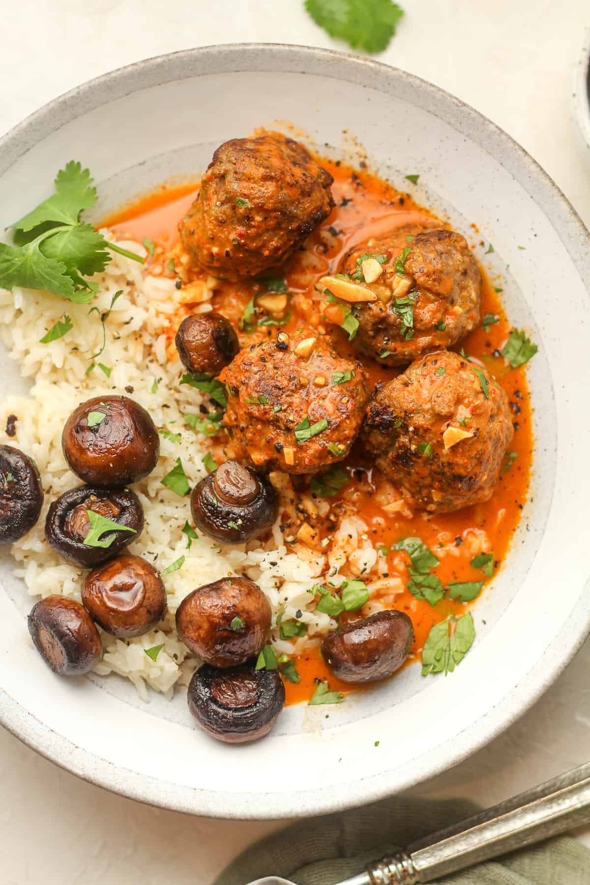 Overhead view of curried meatballs over rice and mushrooms.