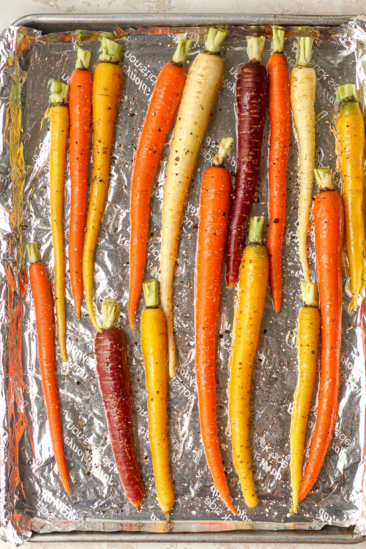 A foil lined pan with the raw and trimmed whole carrots.