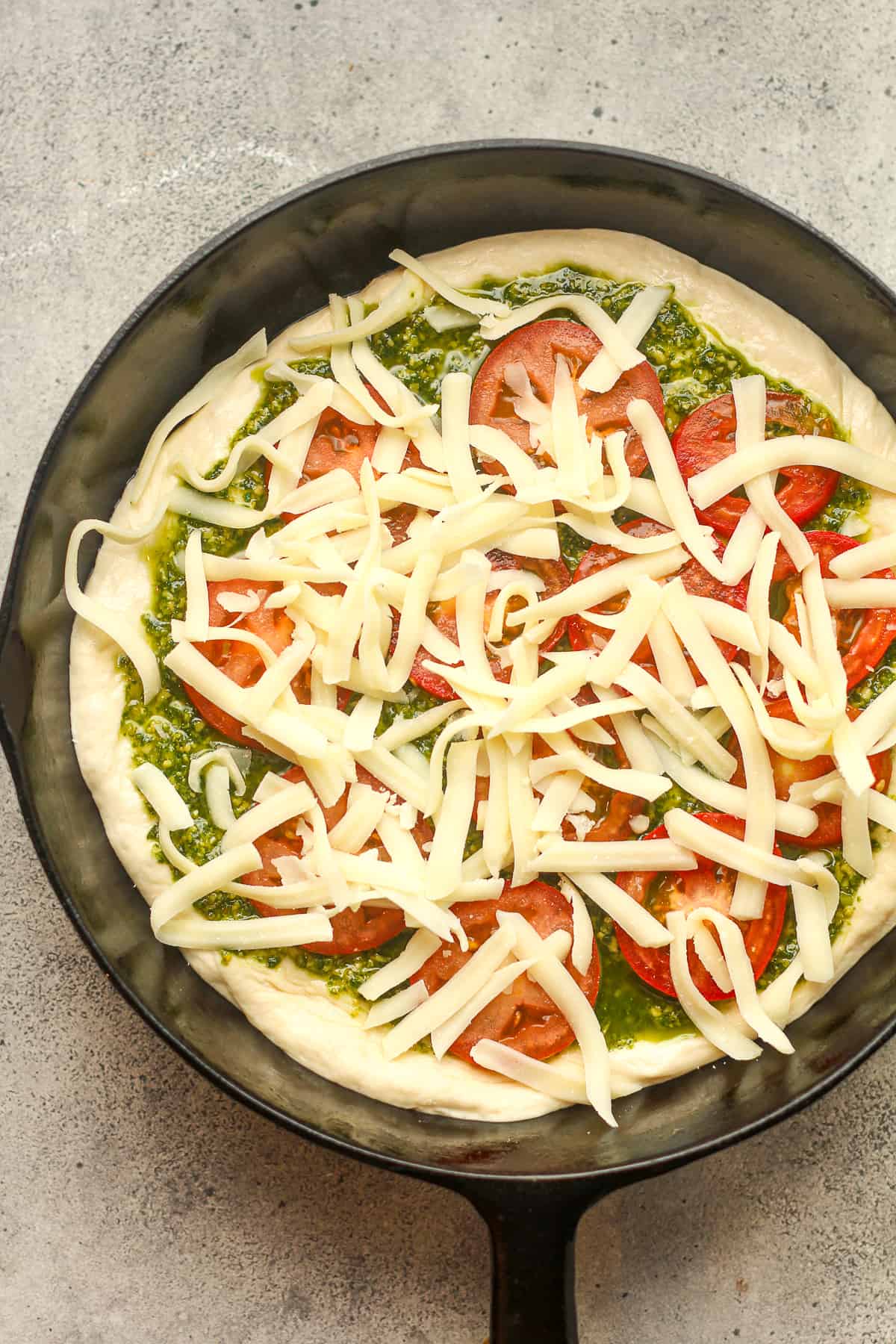A skillet of the pesto pizza before baking.